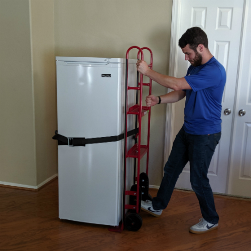 Moving Professional tightening the belt handle to secure an appliance to an appliance dolly