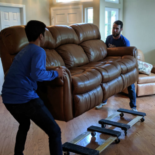 Delivery professionals lifting large couch onto furniture dollies