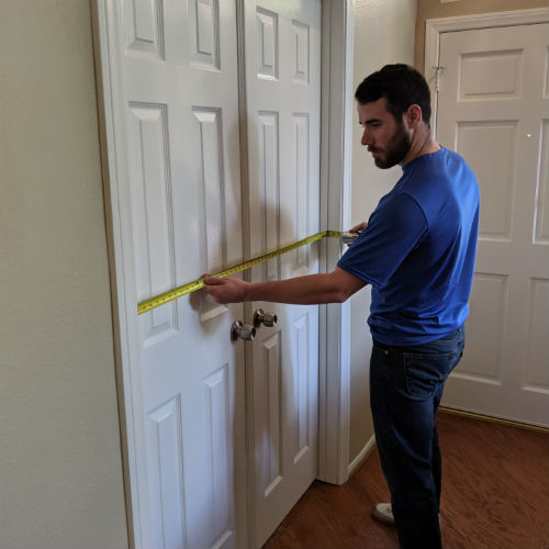 delivery professional using measuring tape to measure a set of french door